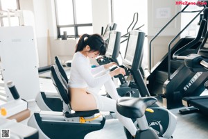 A naked woman standing in front of a gym machine.