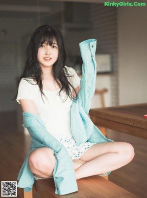 A woman sitting on a white couch wearing a school uniform.