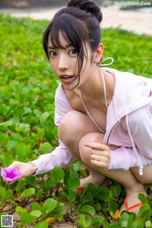 A woman sitting on a rock by the water.