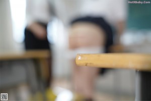 A woman in a school uniform is sitting at a desk.