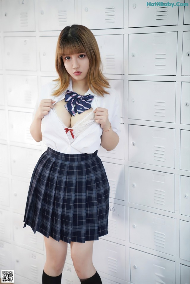 A woman in a school uniform posing in front of lockers.