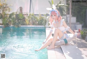 A woman in a bunny costume standing next to a swimming pool.