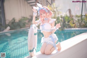 A woman in a bunny costume posing by a pool.