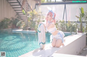 A woman in a bunny costume sitting on the edge of a pool.