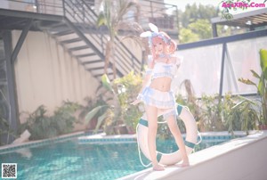 A woman in a bunny costume standing next to a swimming pool.