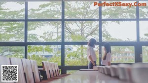 A couple of young women hugging each other on a bench.
