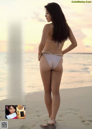 A woman in a yellow bikini sitting on a beach.