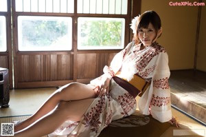 A naked woman sitting on a bed in front of a window.