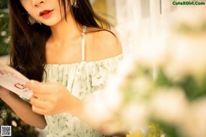 A woman in a green dress holding a bunch of flowers.