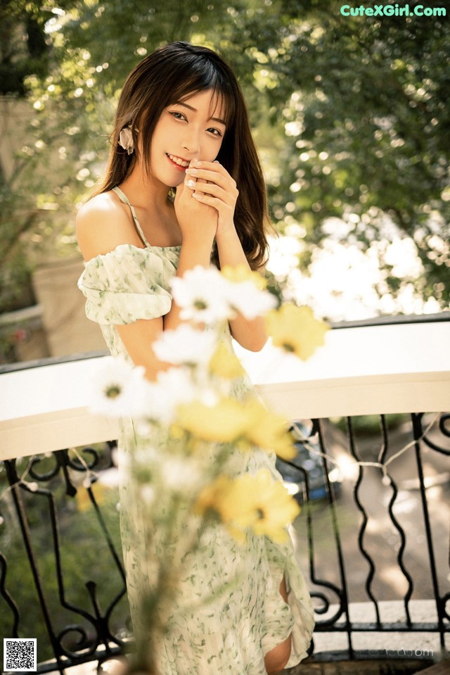 A woman in a green dress standing on a balcony.