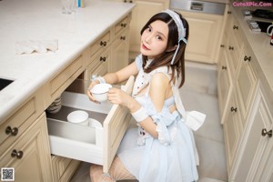 A woman in a white dress sitting on a kitchen counter.