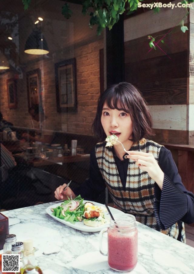 A woman sitting at a table with a plate of food.