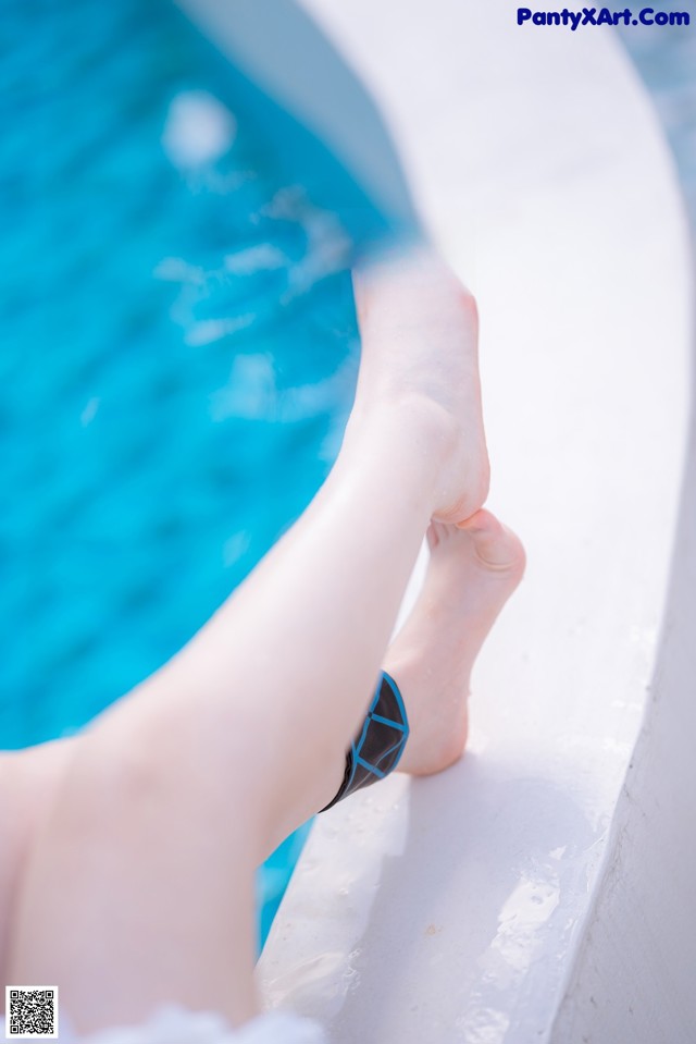 A woman's bare feet by a swimming pool.