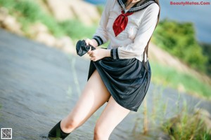 A woman in a school uniform sitting in the water.