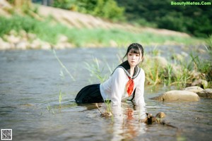 A woman in a school uniform is sitting in the water.