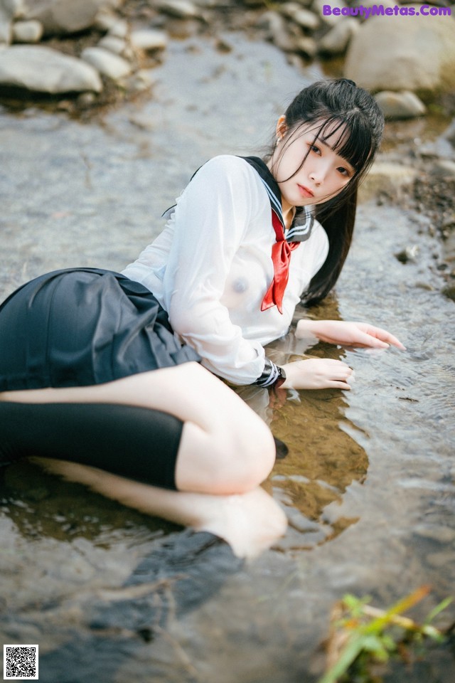 A woman in a school uniform is sitting in the water.