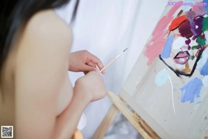 A woman sitting on a chair in front of a painting.