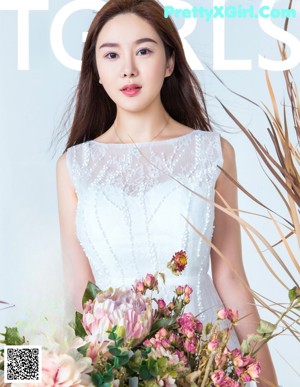 A woman in a white dress sitting on a stool.