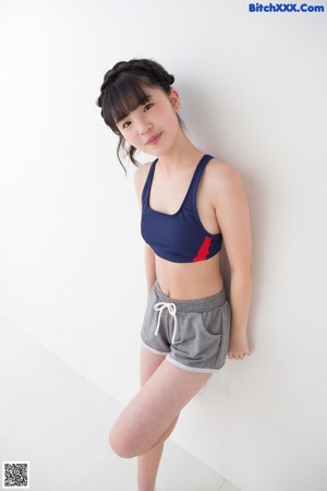 A woman in a sports bra top and shorts posing for a picture.