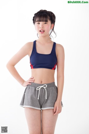 A woman in a blue sports bra top and gray shorts.
