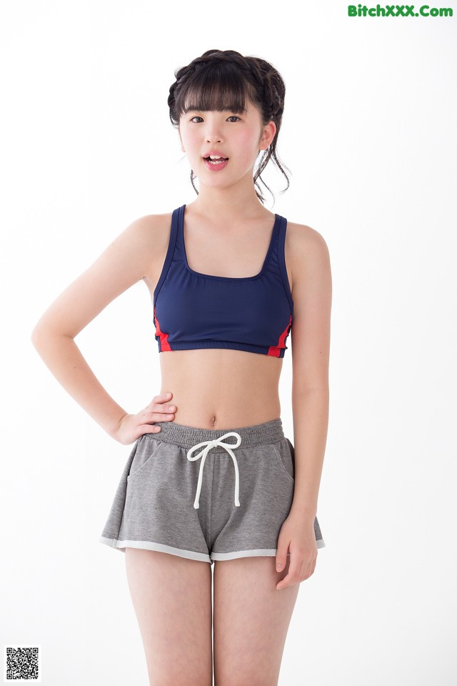 A woman in a sports bra top and shorts posing for a picture.