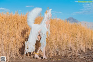 A woman in a white outfit holding a bunch of wheat.