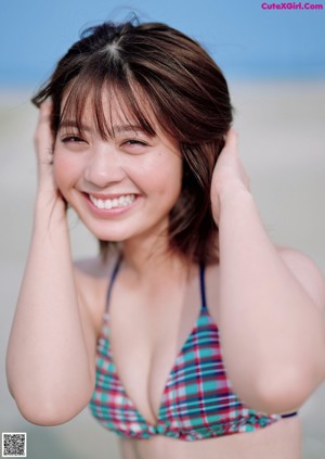 A woman in a bikini posing on a beach.