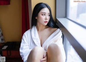 A woman in a white robe laying on a bed.