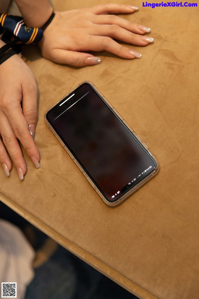 A woman's hands holding a cell phone on a table.