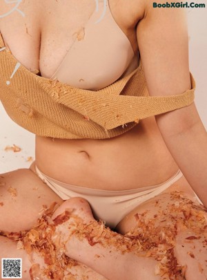 A woman sitting on the ground covered in shredded paper.