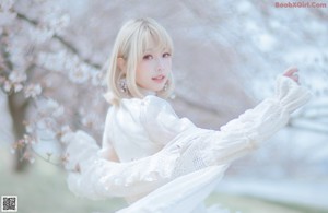 A woman in a white dress sitting under a tree.