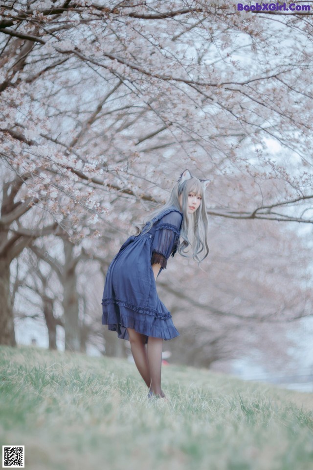 A woman in a blue dress standing in a field of grass.