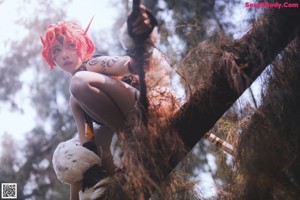 A woman with red hair sitting on the ground.