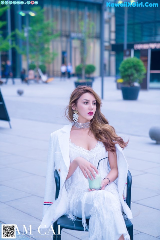 A woman in a white dress sitting on a chair.