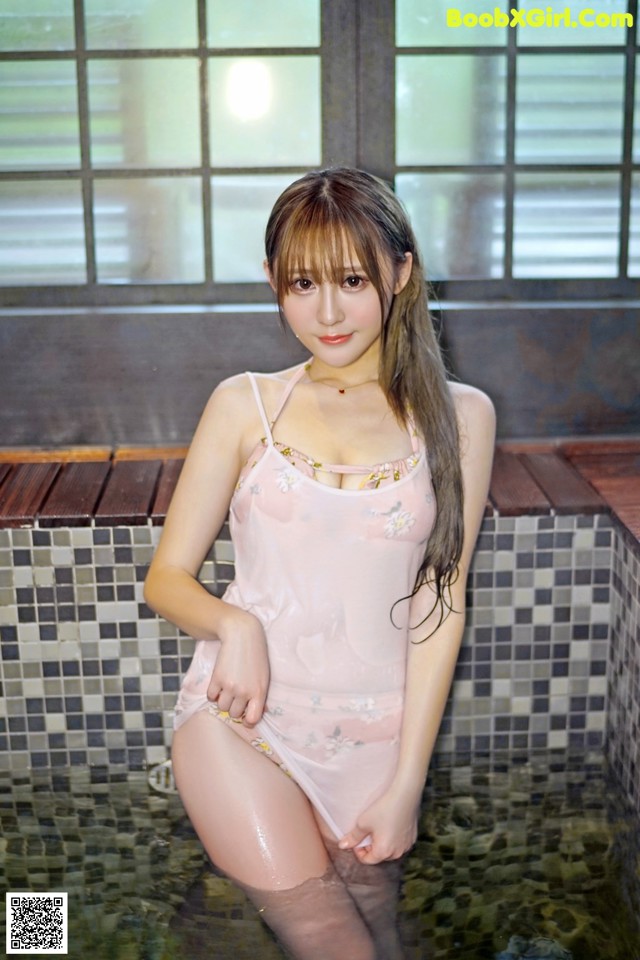 A woman in a pink bathing suit sitting in a pool.