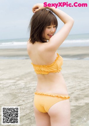 A woman in a pink sweater and striped bikini posing for a magazine.