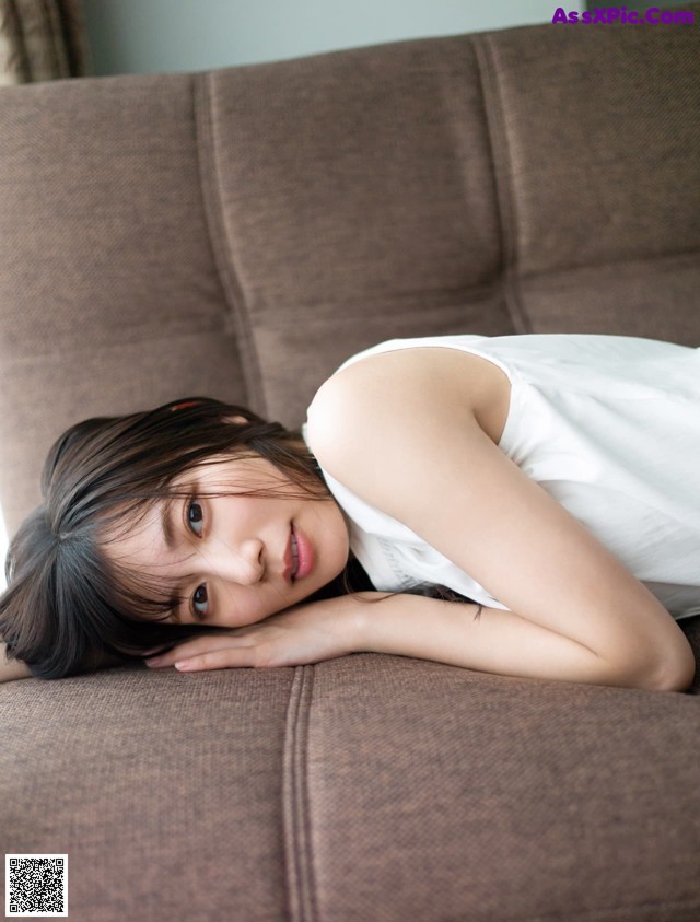 A woman laying on top of a brown couch.