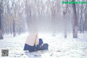 A woman is running in the snow in a park.
