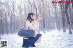 A woman in a white sweater and blue skirt standing in the snow.