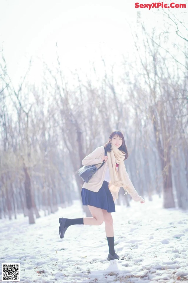 A woman is running in the snow in a park.