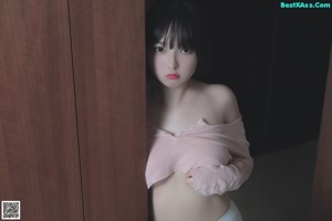 A woman in a white top and panties sitting on a bed.