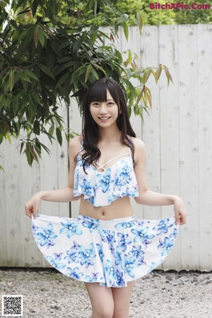 A woman in a blue and white floral top posing for a picture.