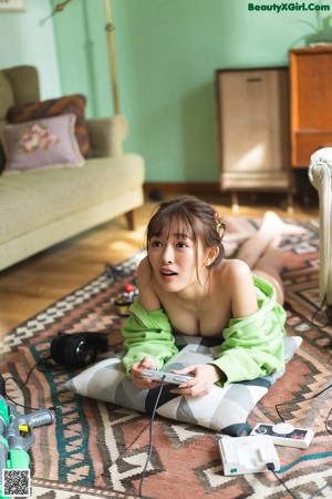 A woman sitting on a couch wearing headphones and holding a Nintendo Switch.