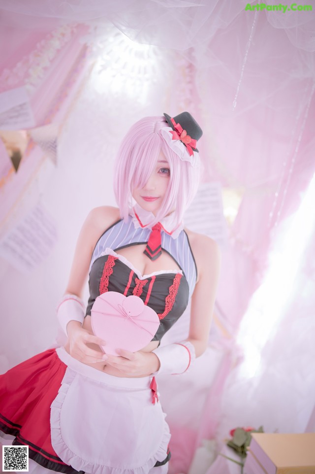 A woman dressed in a maid outfit holding a pink heart.