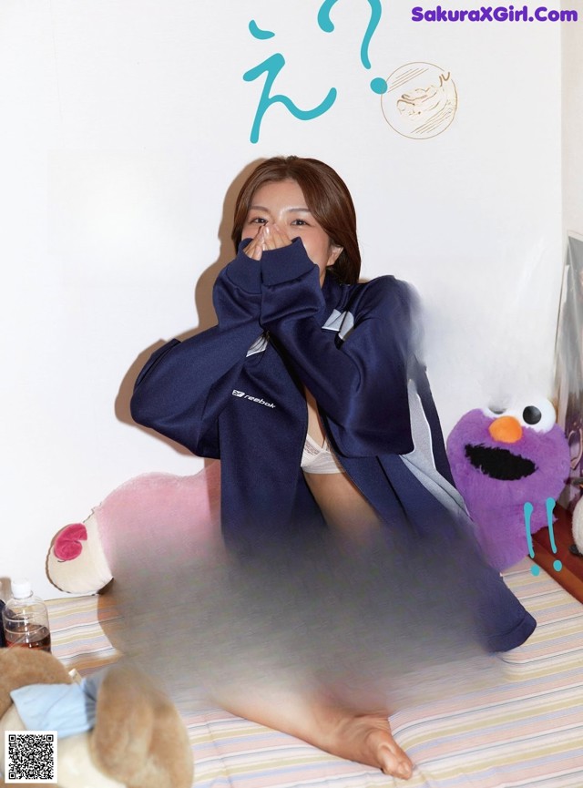 A woman sitting on top of a bed next to a stuffed animal.