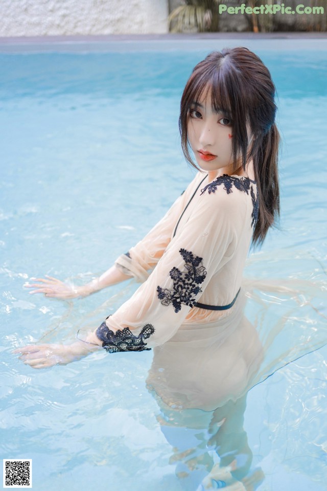 A woman in a white dress is standing in a pool.