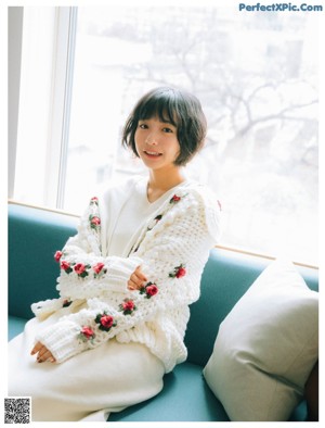 A woman in a white polka dot dress smiles at the camera.