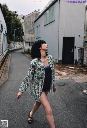 A woman standing in front of a concrete wall.