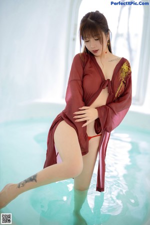 A woman in a red robe standing in a pool.