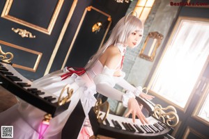 A woman in a white dress playing a white piano.